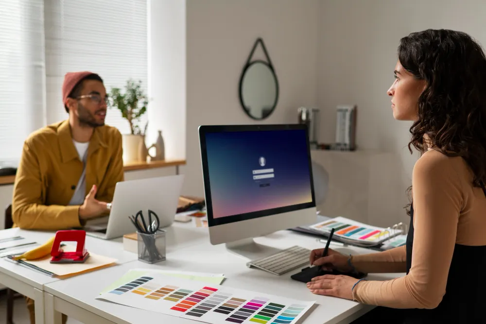 Dois designers trabalhando em uma mesa com amostras de cores